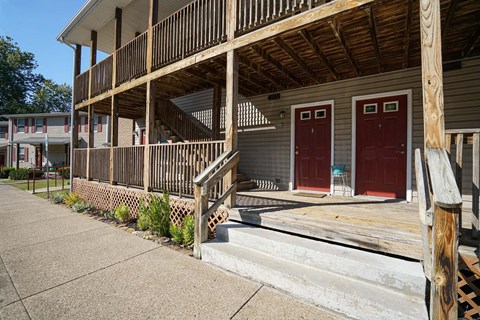 the front of a building with two red doors and a porch
