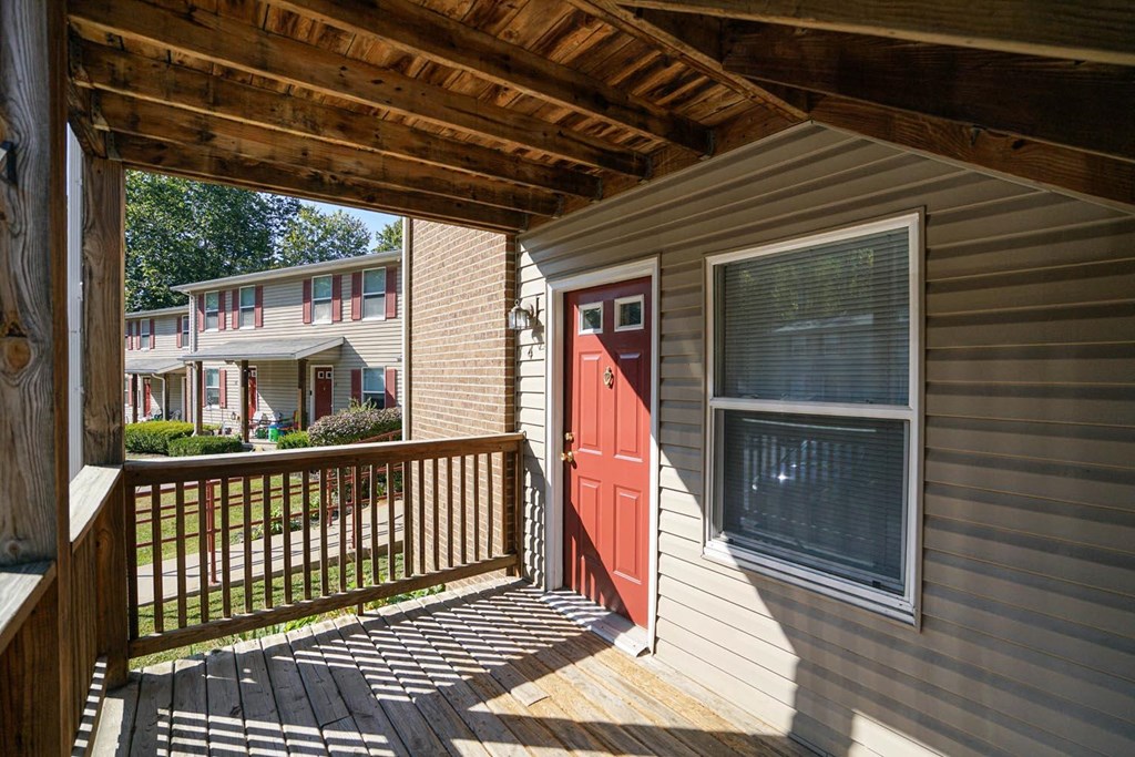 the front porch of a home with a red door