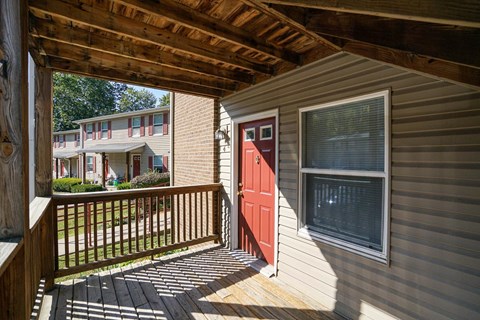 the front porch of a home with a red door