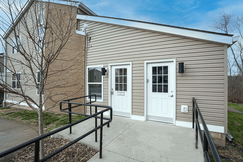 the front of a building with a white door and a ramp