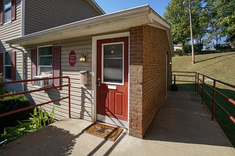 the front porch of a house with a red door