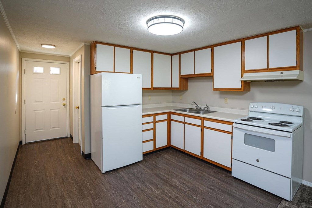 an empty kitchen with white appliances and white cabinets