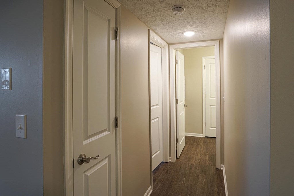 a hallway with white doors and a door to a closet