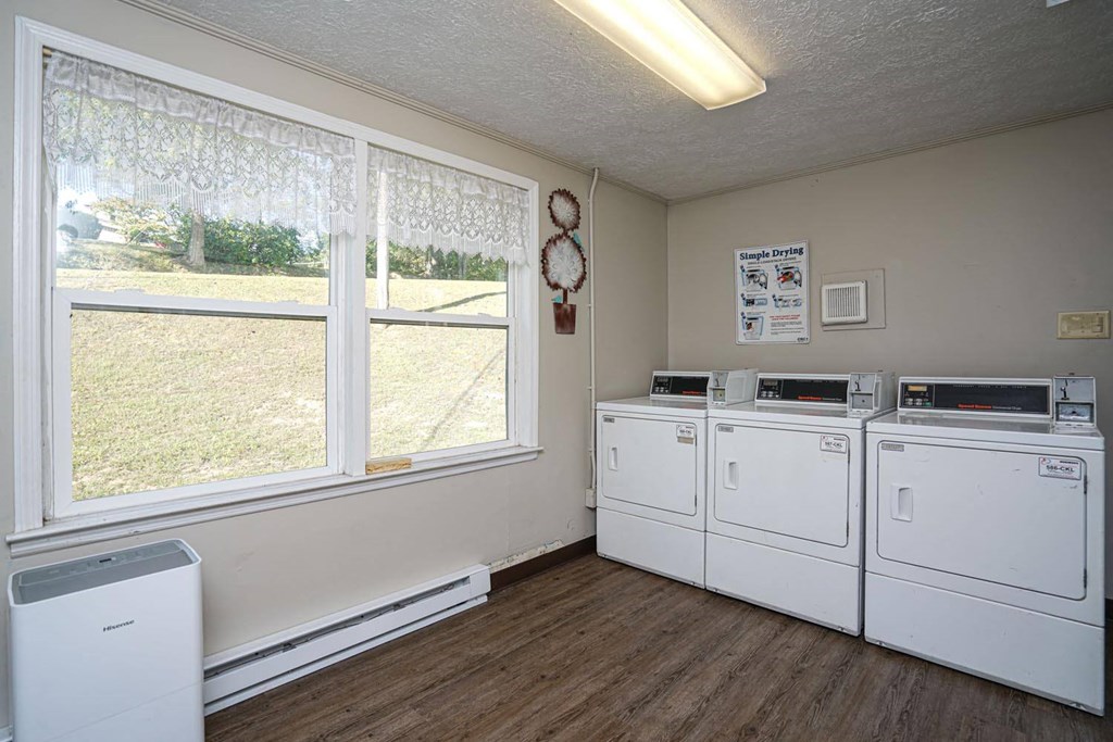a laundry room with four washer and dryers and a large window