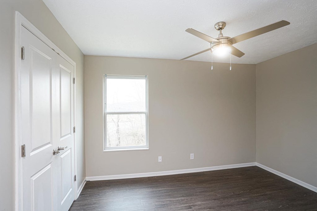 an empty room with a ceiling fan and a window