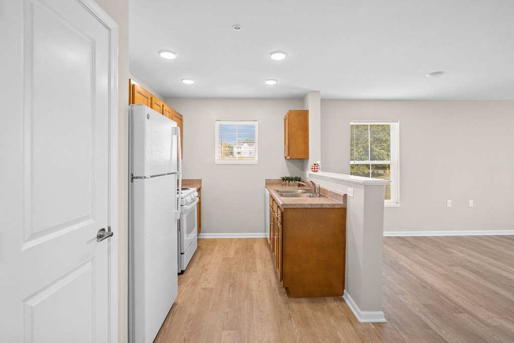 an empty kitchen with white appliances and wood floors