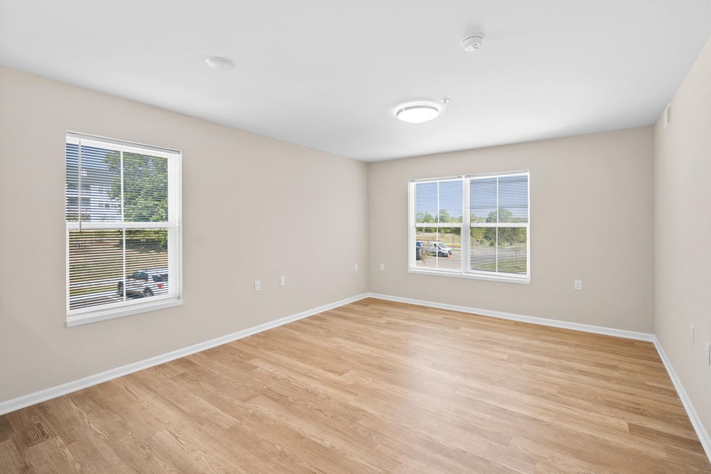 an empty room with wood floors and two windows