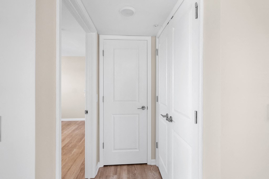 an empty hallway with white doors and a wood floor