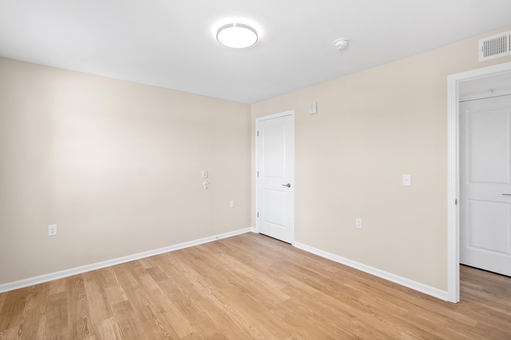a bedroom with white walls and wood flooring and a door