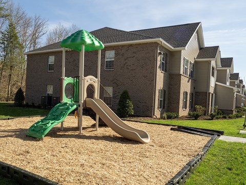a playground with a slide in front of an apartment building