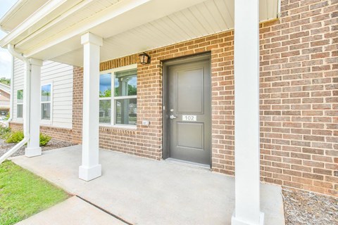 the front door of a brick house with two pillars in front of it