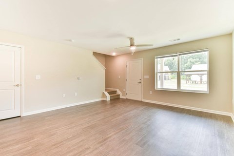 an empty living room with a ceiling fan and a window