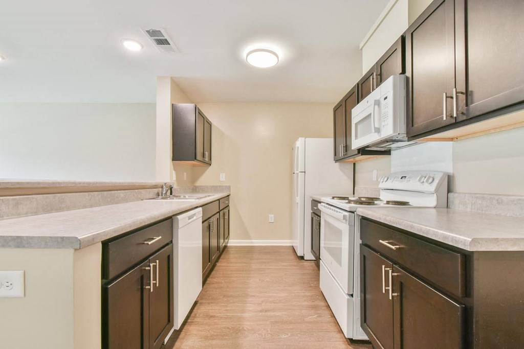 a kitchen with dark cabinets and white appliances