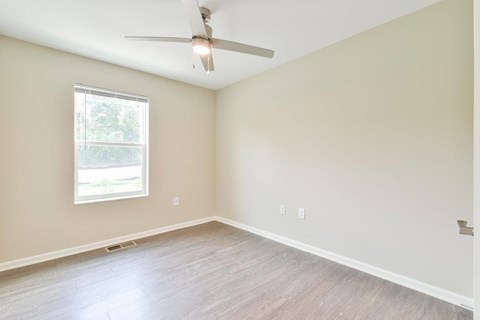 one of the bedrooms with hardwood floors and a ceiling fan
