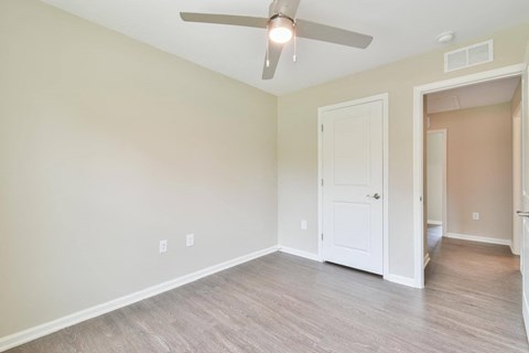 a bedroom with a ceiling fan and a door to a bathroom