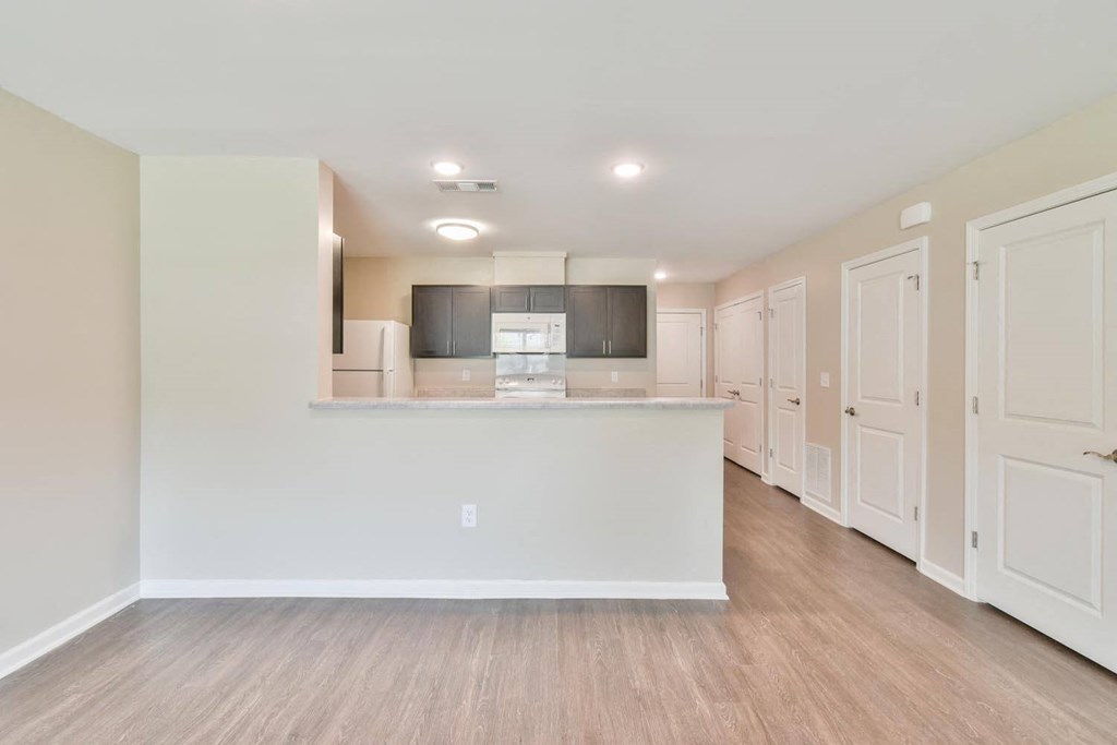 a kitchen and living room with white walls and wood floors
