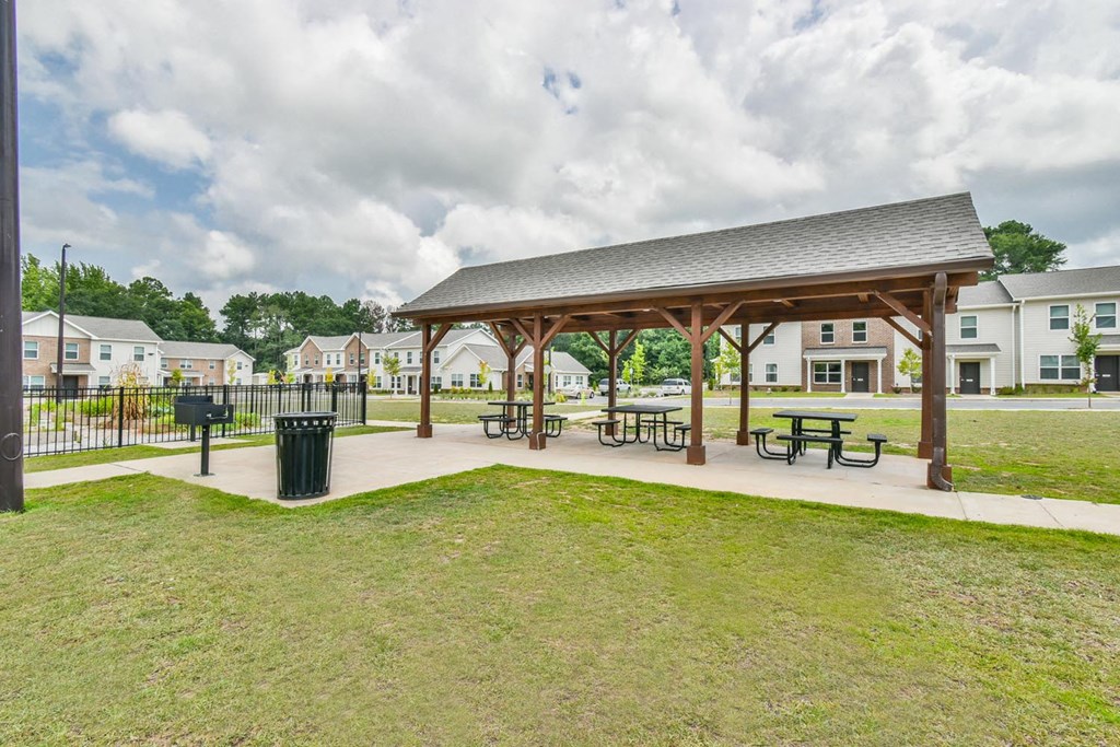 a pavilion with picnic tables and a trash can at the whispering winds apartments in pearland