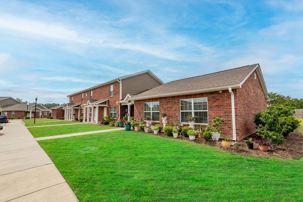 a row of houses on a street with a green lawn and potted plants