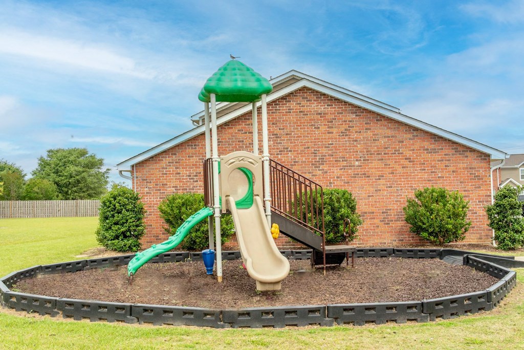 a playground with a slide in front of a brick building
