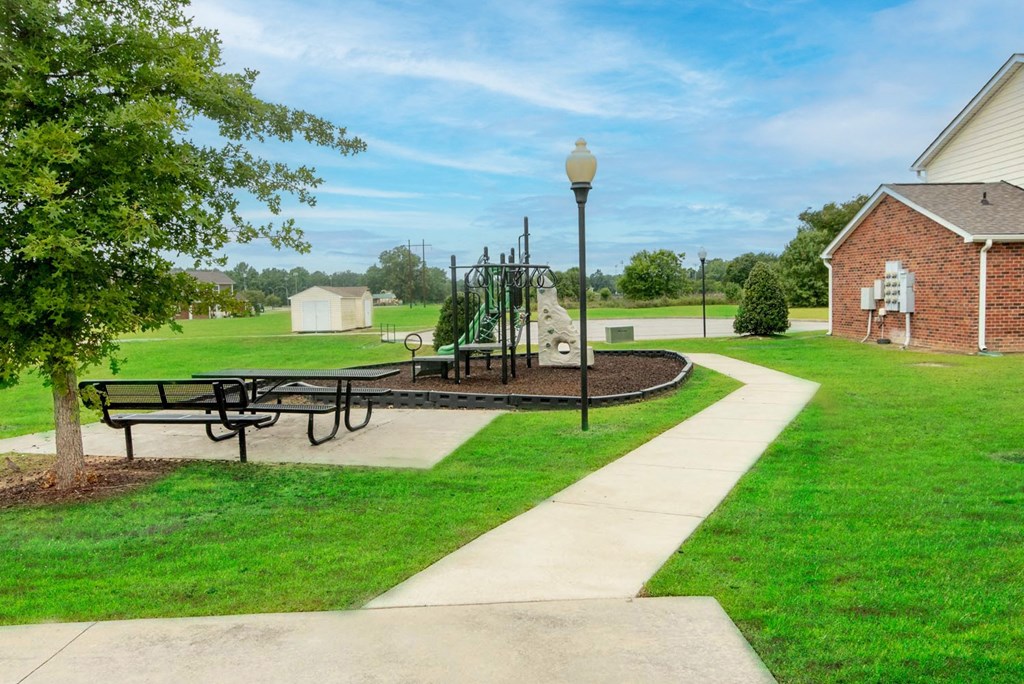 a picnic area with a playground in the background