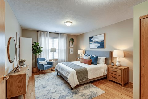A bedroom with a large bed, a chair, and a painting on the wall.