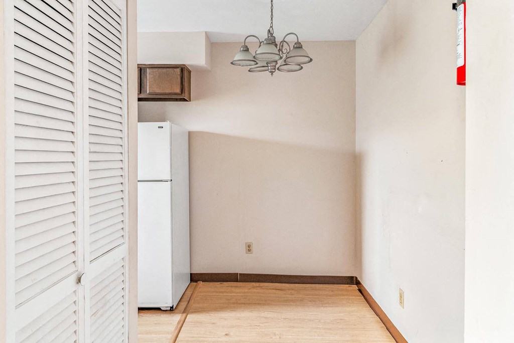 a room with a white refrigerator and a chandelier