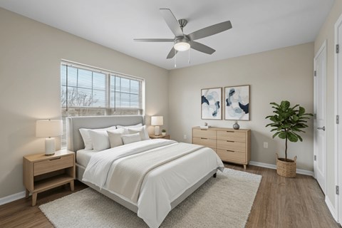 A bedroom with a large bed, a ceiling fan, and a plant.