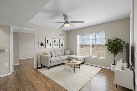 A living room with a grey couch, a coffee table, and a ceiling fan.
