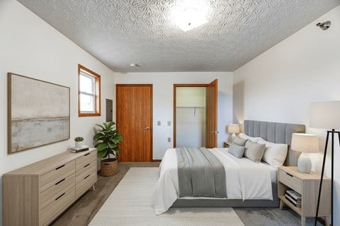 A bedroom with a bed, nightstand, and a painting on the wall.