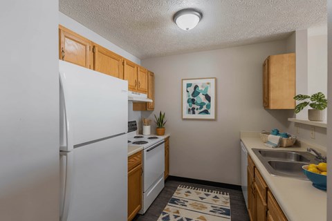 A kitchen with a white refrigerator and wooden cabinets.