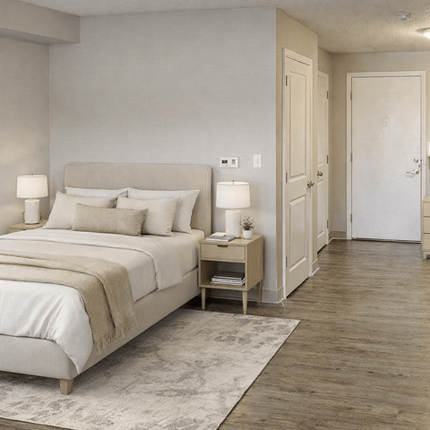 A bedroom with a large bed and a nightstand with a lamp.