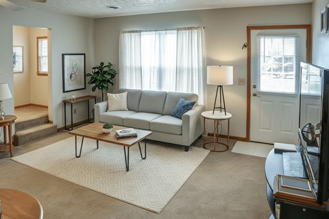 A living room with a grey couch, a coffee table, and a lamp.