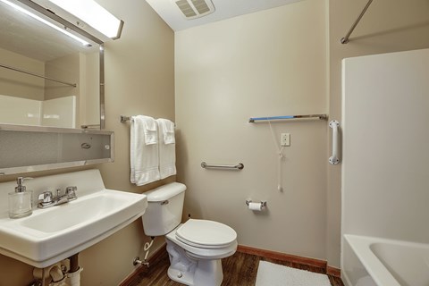 A white toilet sits in a small bathroom with a sink and mirror.