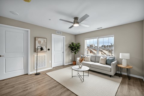 A living room with a white couch, a coffee table, and a ceiling fan.