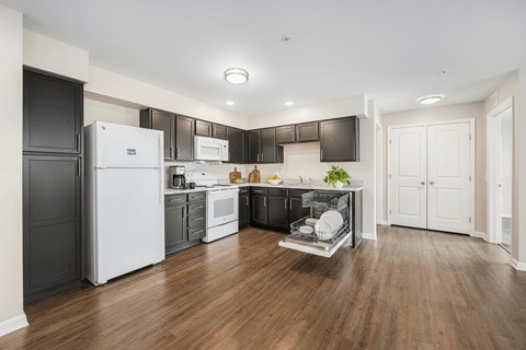 A modern kitchen with wooden floors and white appliances.