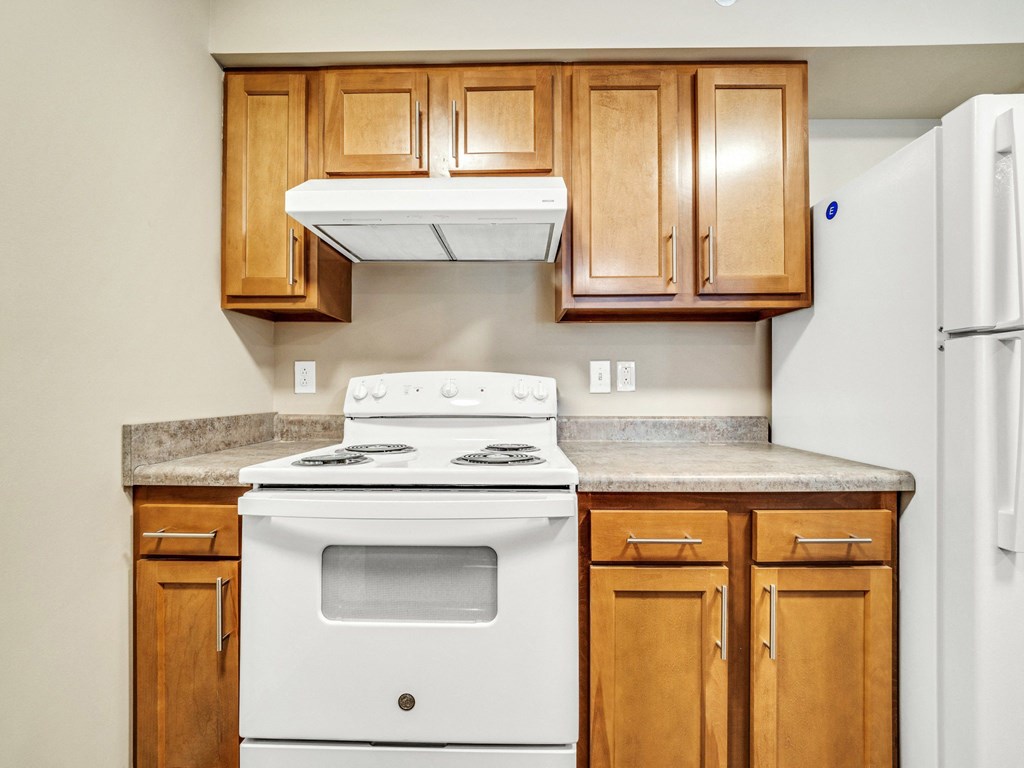 a kitchen with a stove and cabinets and a refrigerator