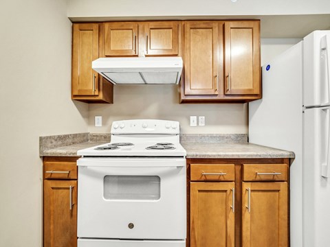 a kitchen with a stove and cabinets and a refrigerator