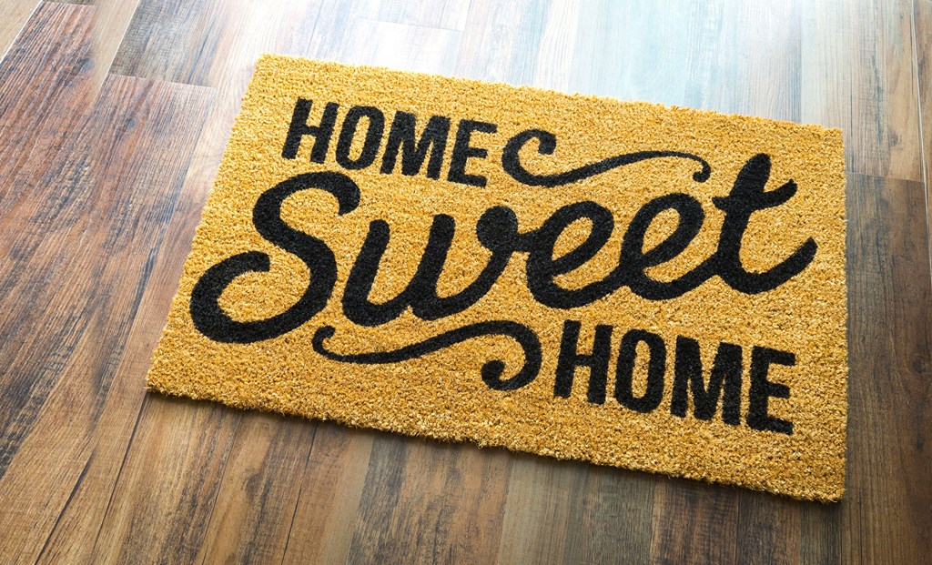 a welcome mat that reads home sweet home on a wood floor