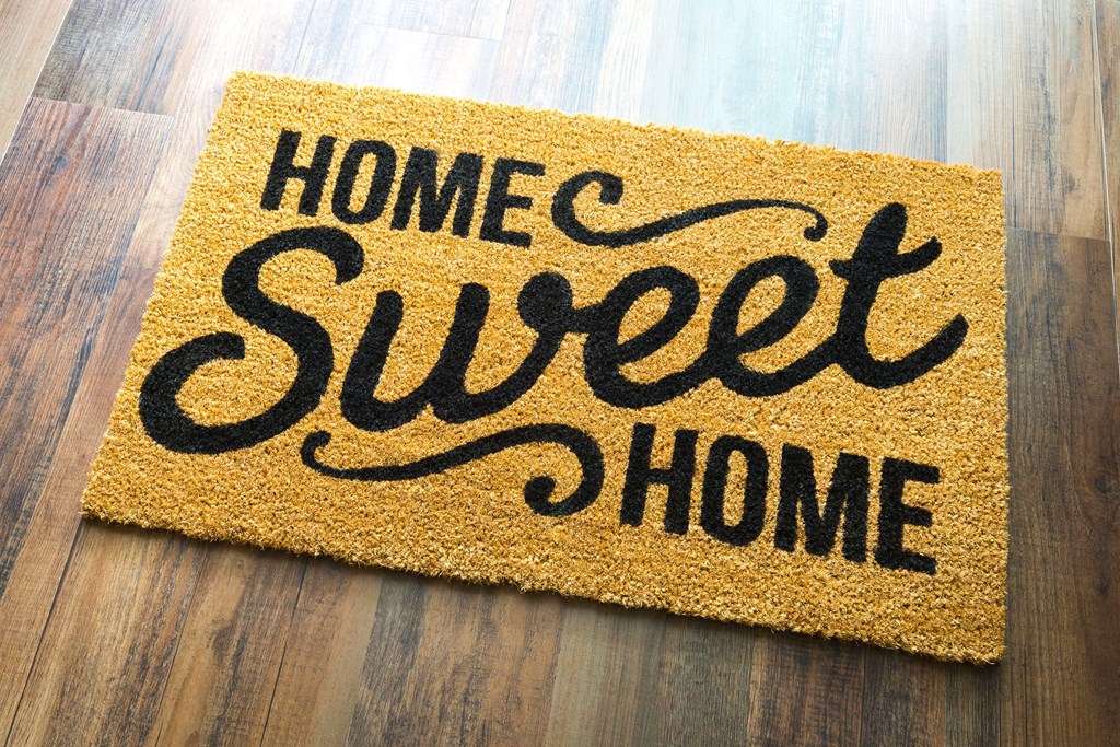 A doormat that says "Home Sweet Home" on a wooden floor.