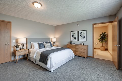 A bedroom with a bed, nightstand, and two lamps.