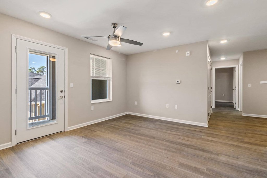 A room with a ceiling fan and a door leading to a balcony.