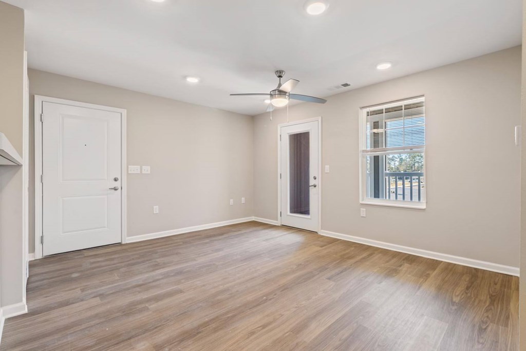 A spacious room with a ceiling fan and a window with blinds.