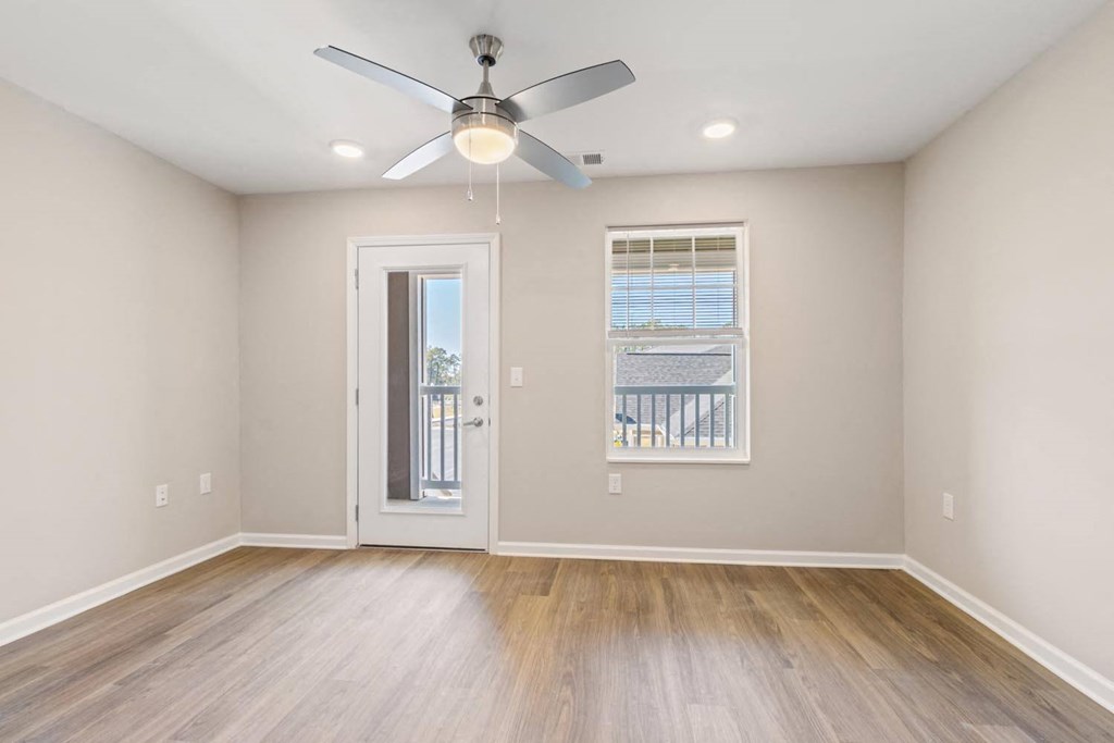 A room with a ceiling fan and a door leading to a balcony.