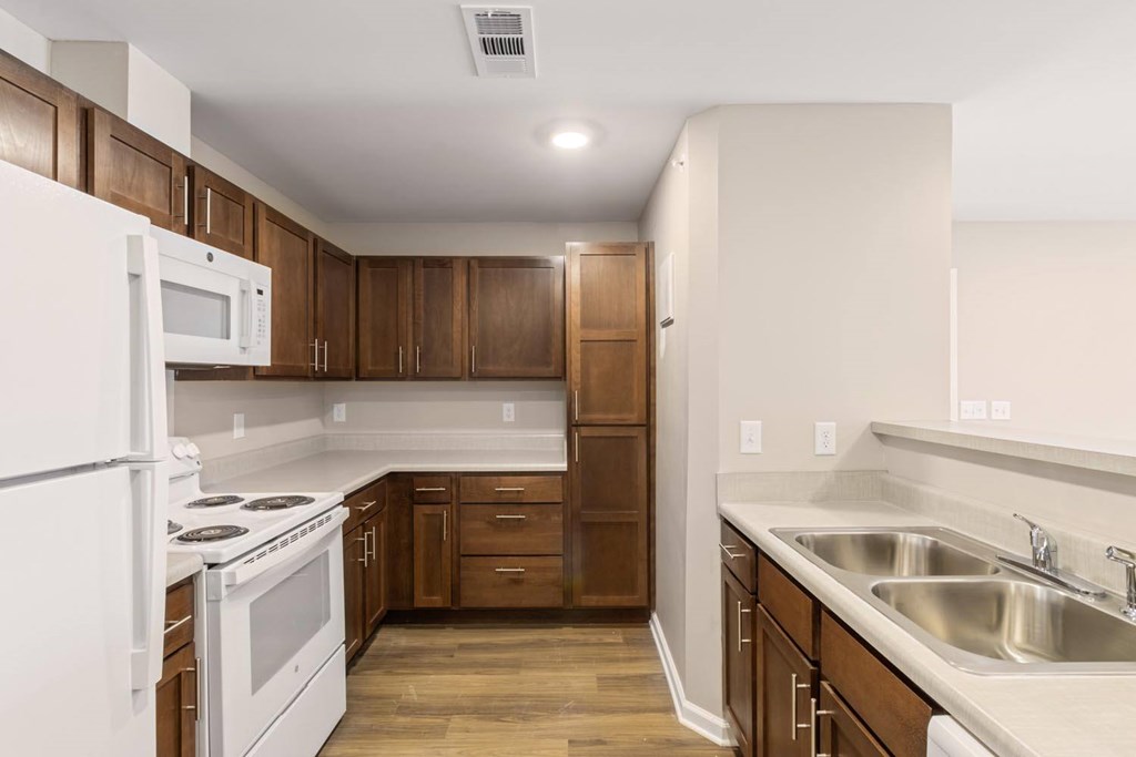 A kitchen with white appliances and wooden cabinets.