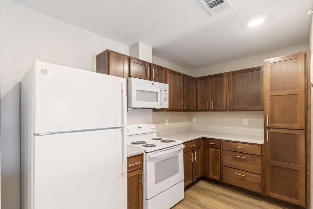 A kitchen with white appliances and wooden cabinets.