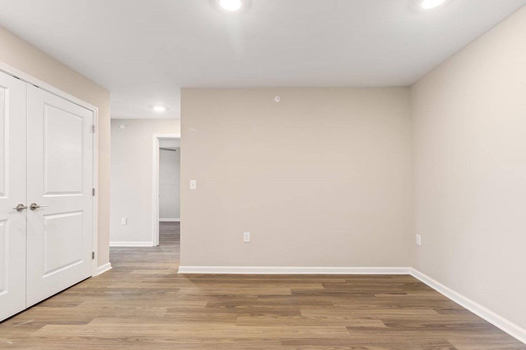 A room with a white door and wooden flooring.