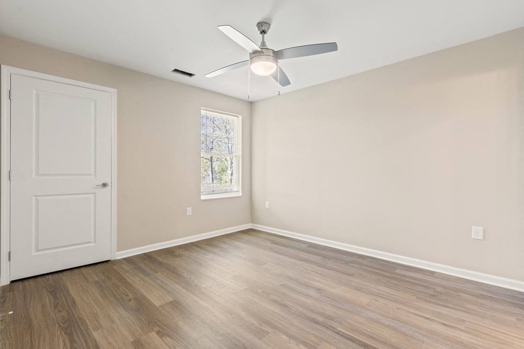 A room with a ceiling fan and a door.