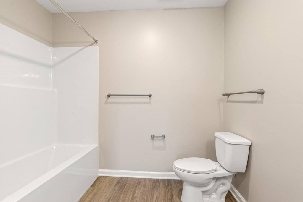 A white toilet in a small bathroom with a white door and a white towel rack.