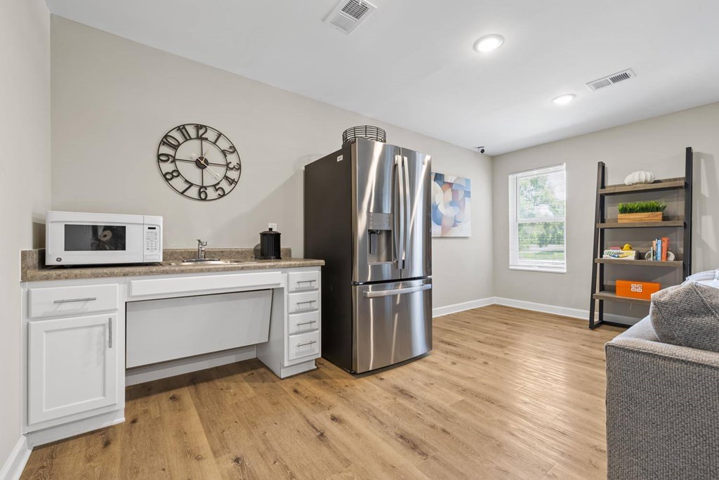 A kitchen with a refrigerator, microwave, and sink.