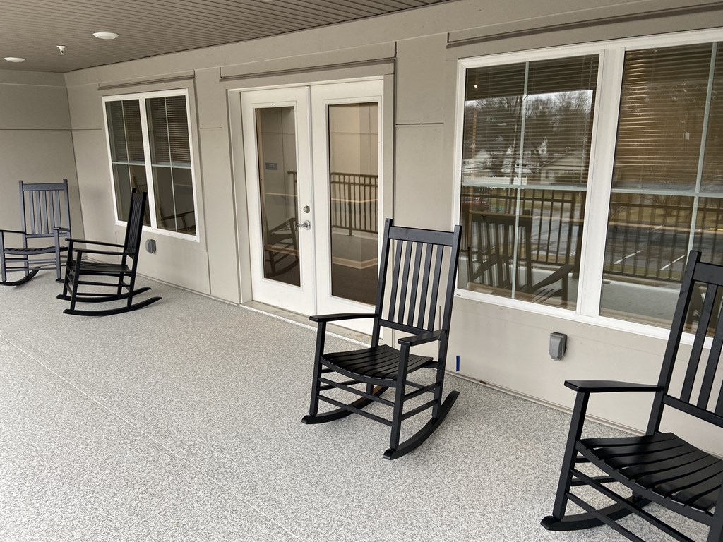 a group of rocking chairs on a porch with windows